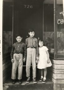 The Tom children stand in front door of family restaurant.
